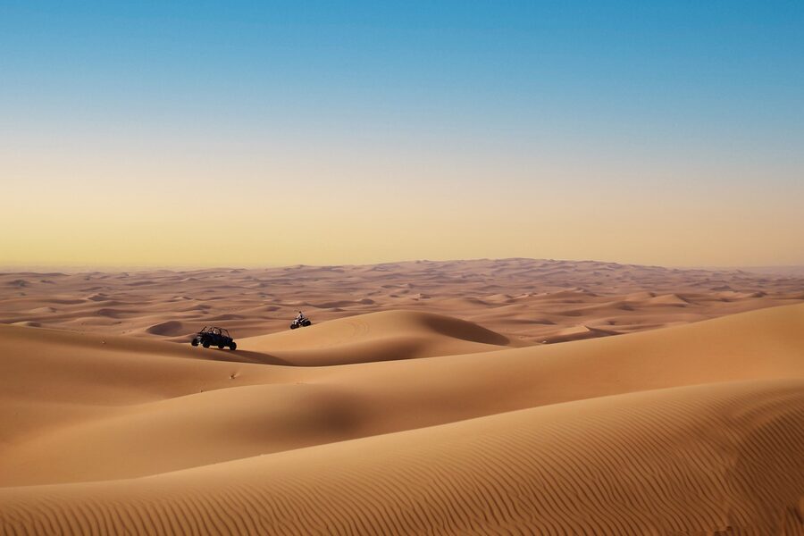 Dune buggy silhouetted against desert sunset