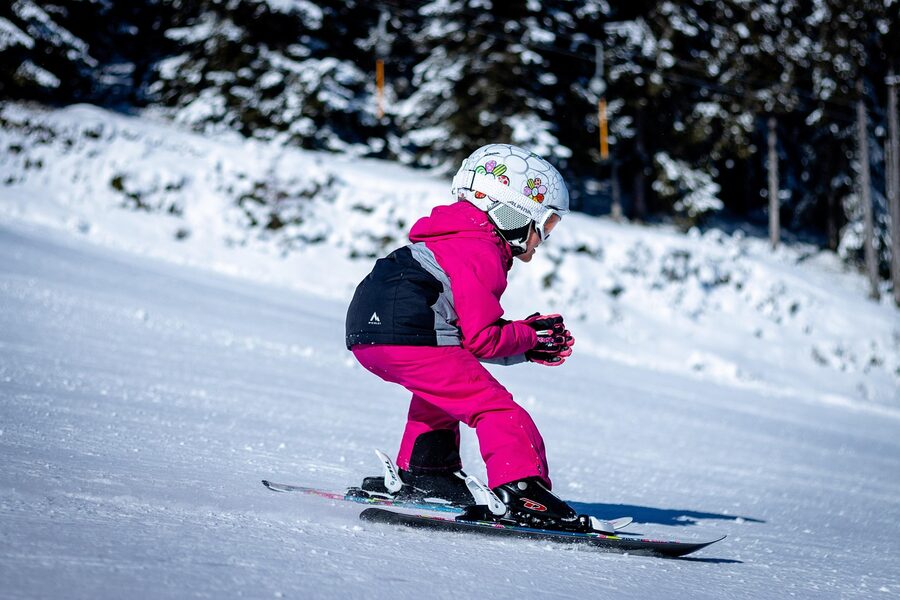 Child skiing on snowy slope wearing winter sports gear