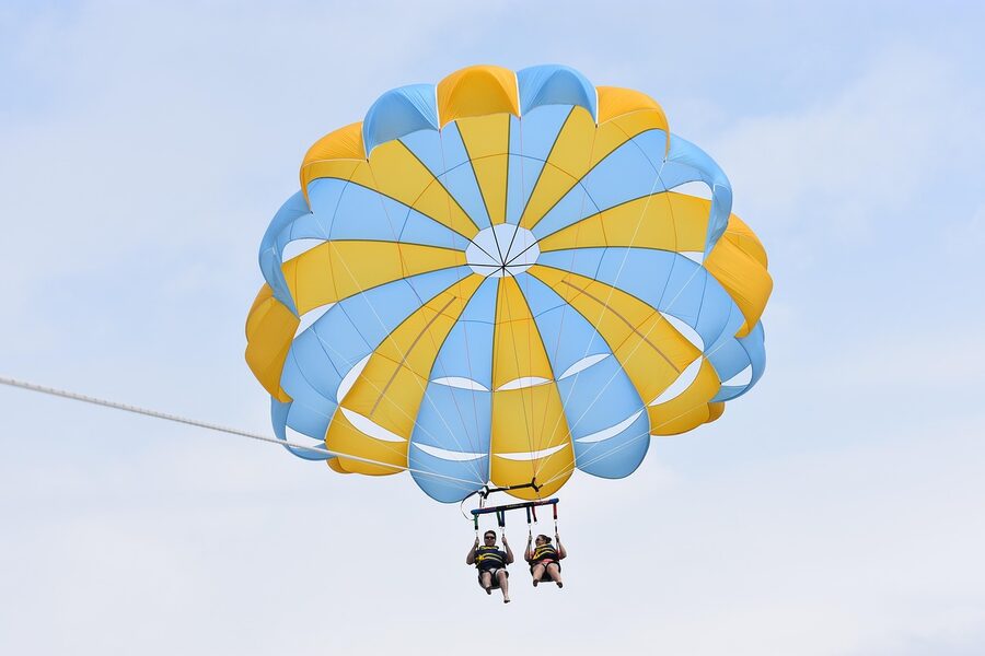 Couple parasailing with colourful parachute above sea