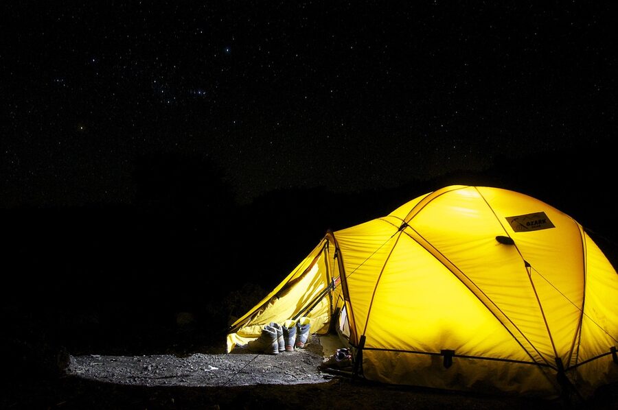 Desert camping tent at night under starry sky with warm glow