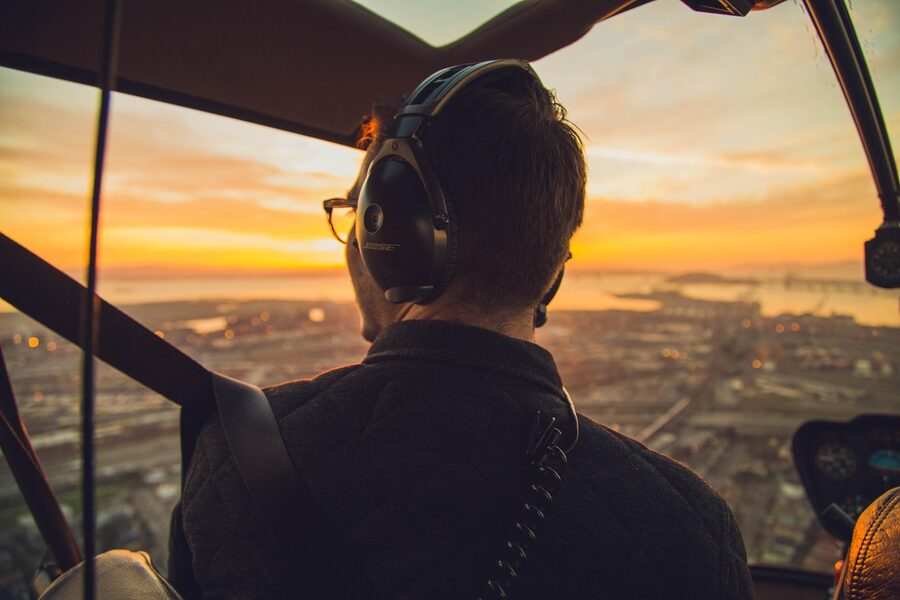 View from helicopter cockpit showing pilot controls and city