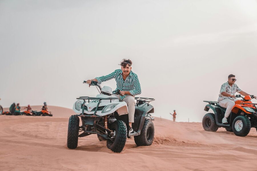 Quad biking across sunlit desert dunes
