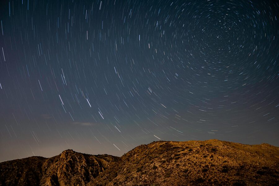 Star trails over desert landscape at night
