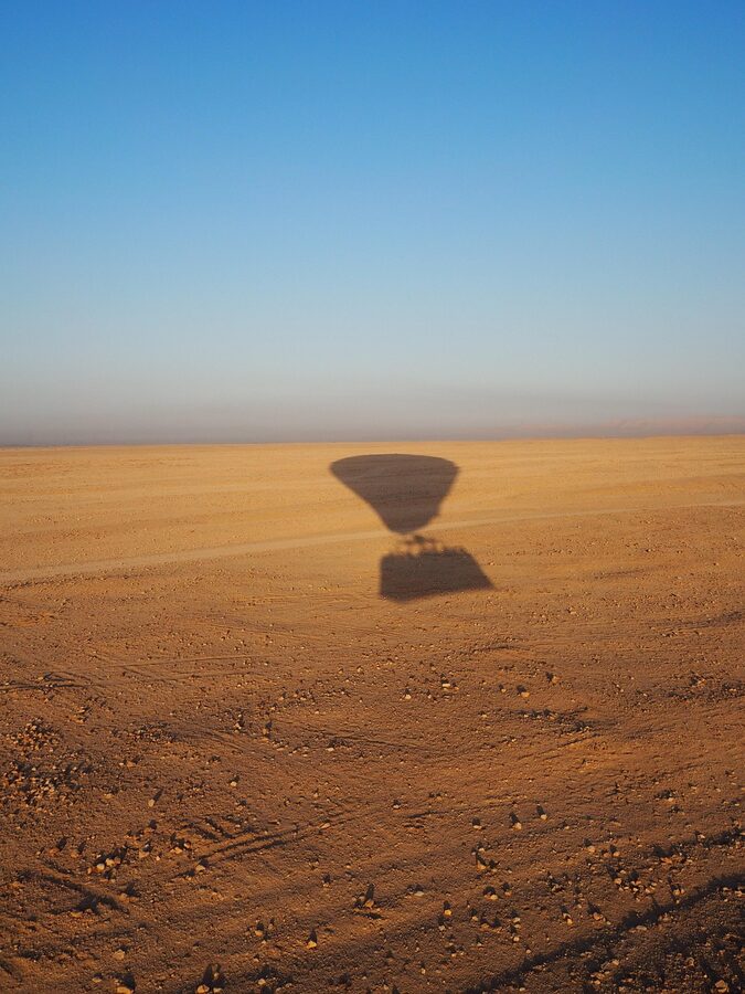 Hot air balloon floating over Luxor desert landscape