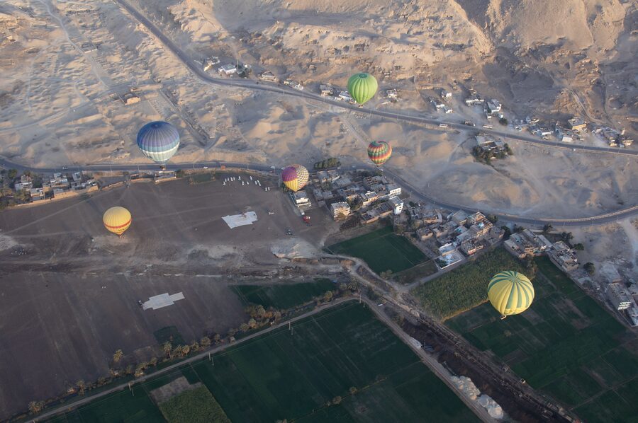 Group of hot air balloons at sunrise over Luxor farmland