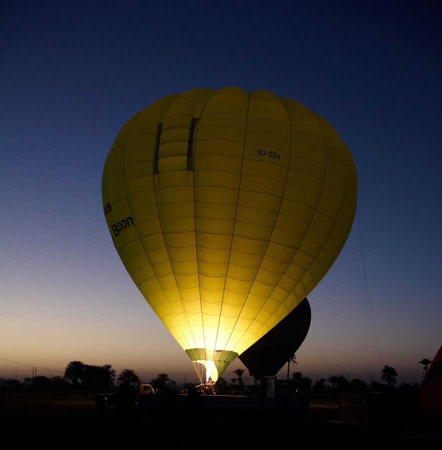 Hot air balloon envelope being inflated with burner flame visible in basket