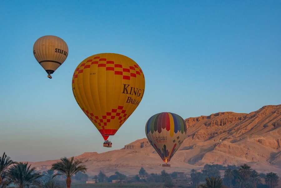 Colorful hot air balloons soaring over Luxor desert landscape at sunrise