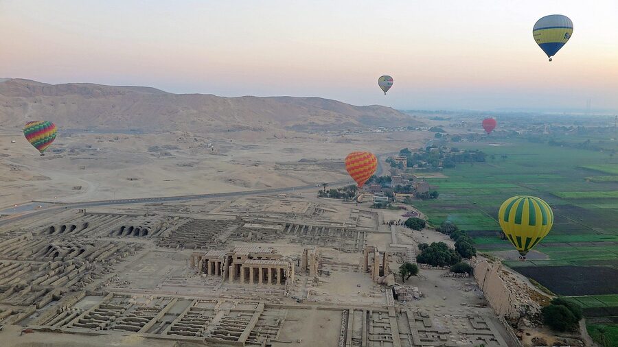 Hot air balloons over Luxor Nile with temple visible below