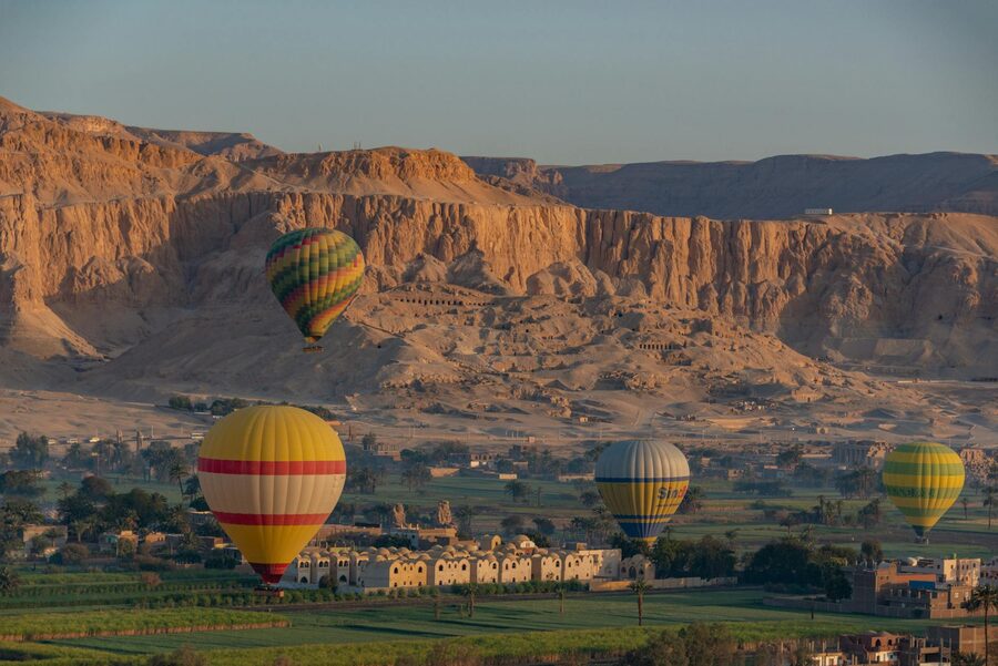 Hot air balloons over Luxor landscape at sunrise with Nile visible