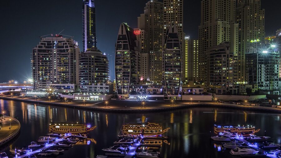 Marina buildings reflected in calm water at night