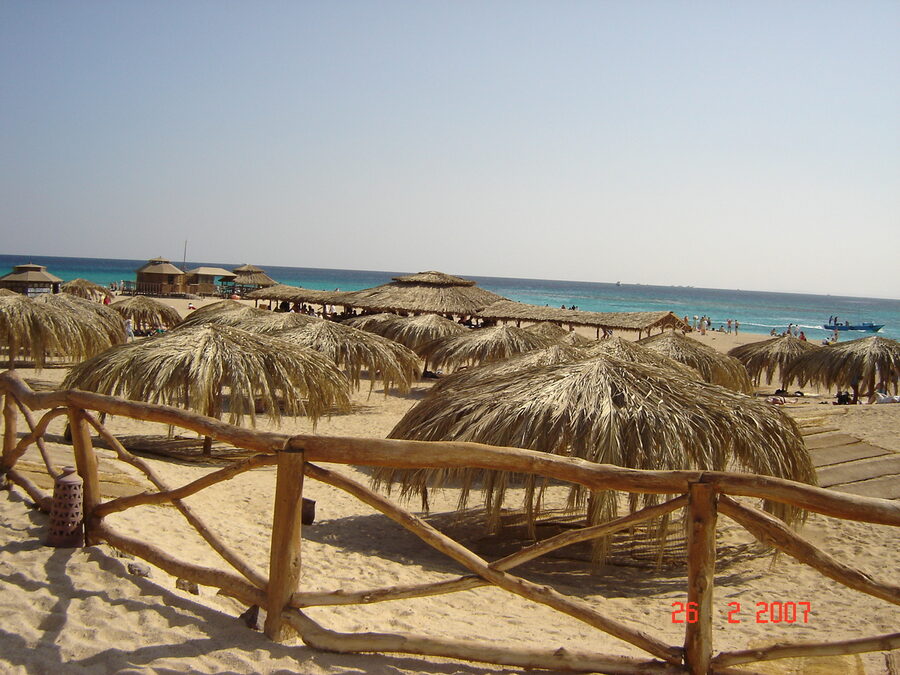 Orange Bay beach with parasols and wooden walkway over shallow turquoise water at Giftun