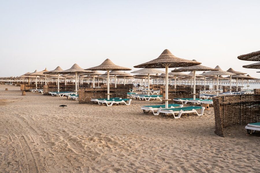 Row of beach umbrellas at Orange Bay with turquoise water and sandbar