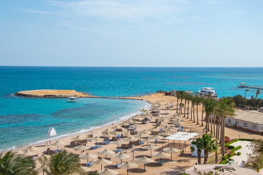 Beach umbrellas on white sand with blue Red Sea water stretching to horizon