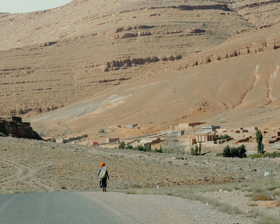 Person walking toward traditional village in Atlas