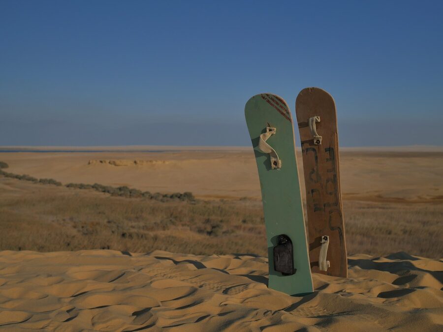Person sandboarding down a desert dune in Dubai