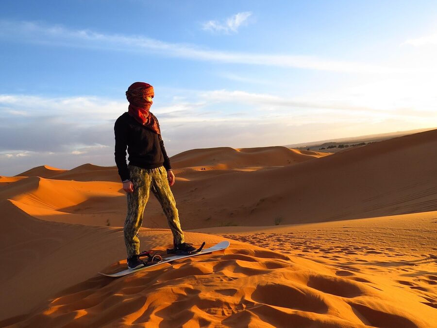 Sandboarding on desert sand dunes with tracks visible in the sand
