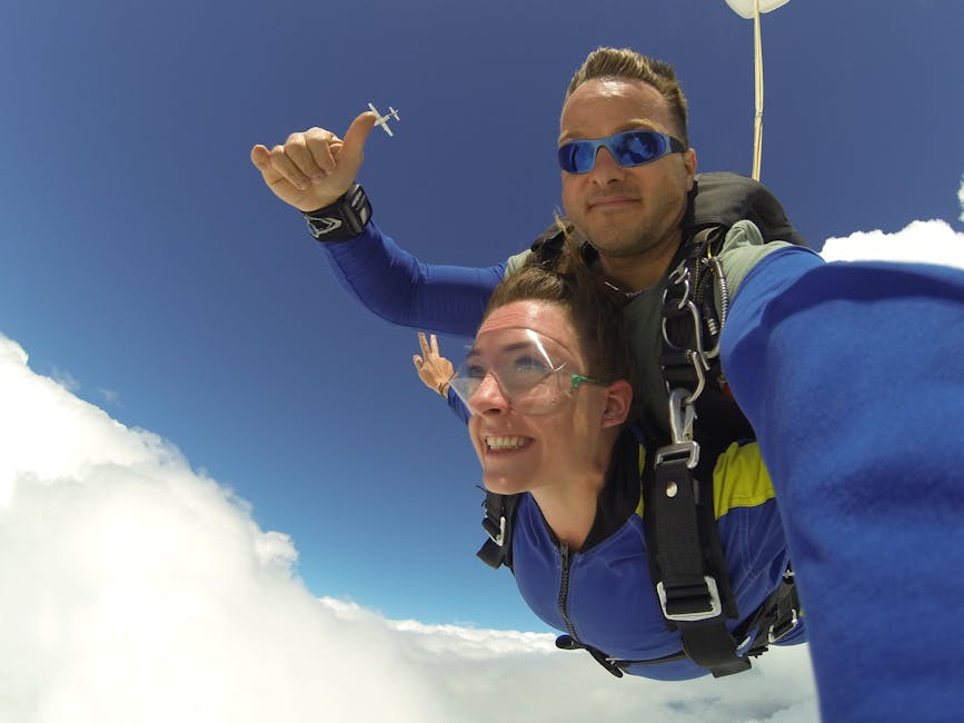 Tandem skydivers in freefall through clouds with arms spread