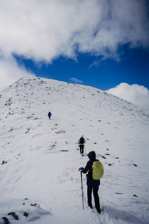 Hikers ascending snowy mountain trail